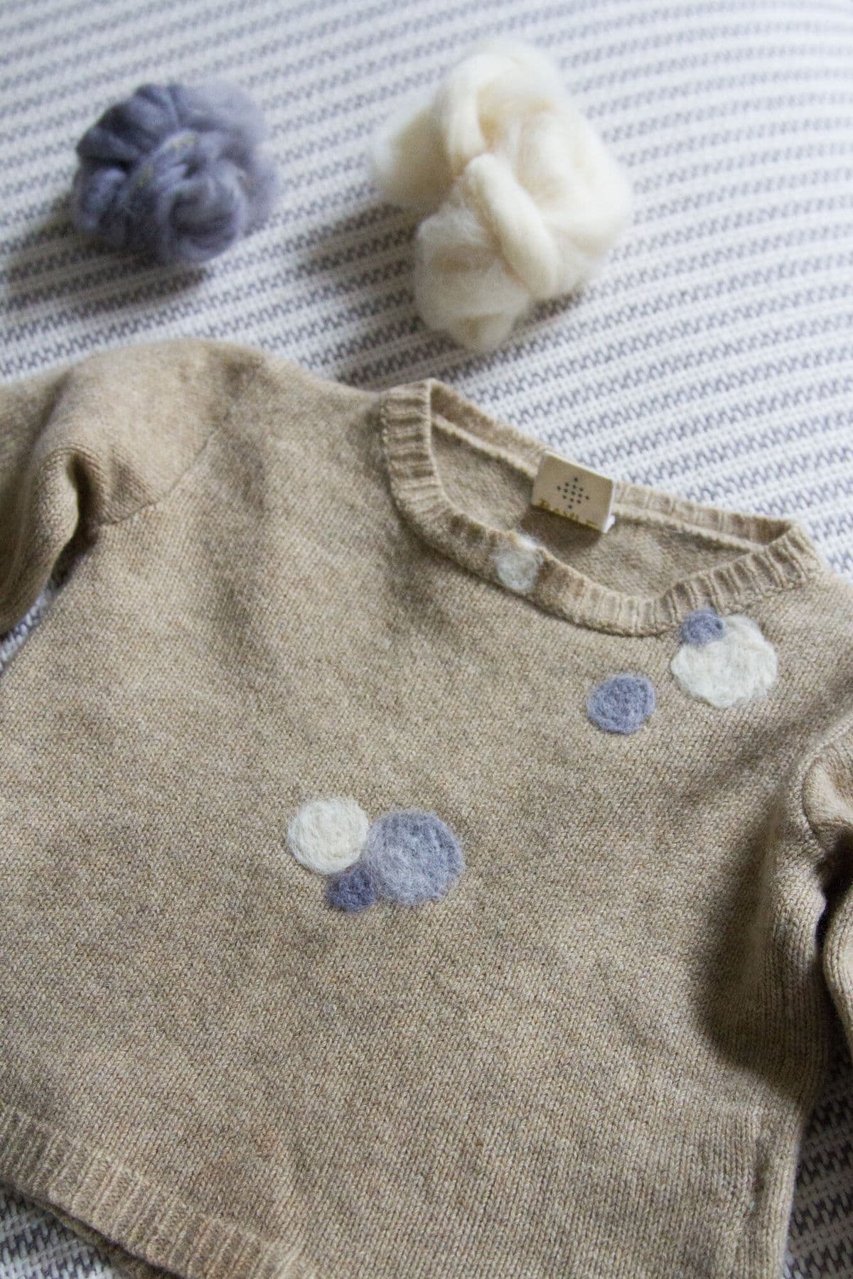 Ronds bleus en feutre sur un pull gris