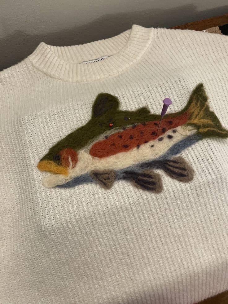 Poisson en feutre sur un pull en laine blanc