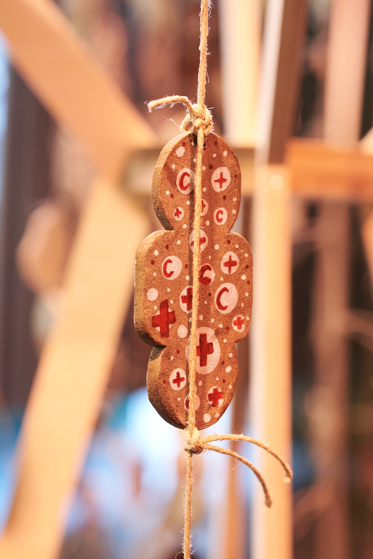 Gros plan sur un objet décoratif suspendu, composé de motifs de croix et demi-lunes rouges dans une lumière chaude, détaché d'un fond flou.