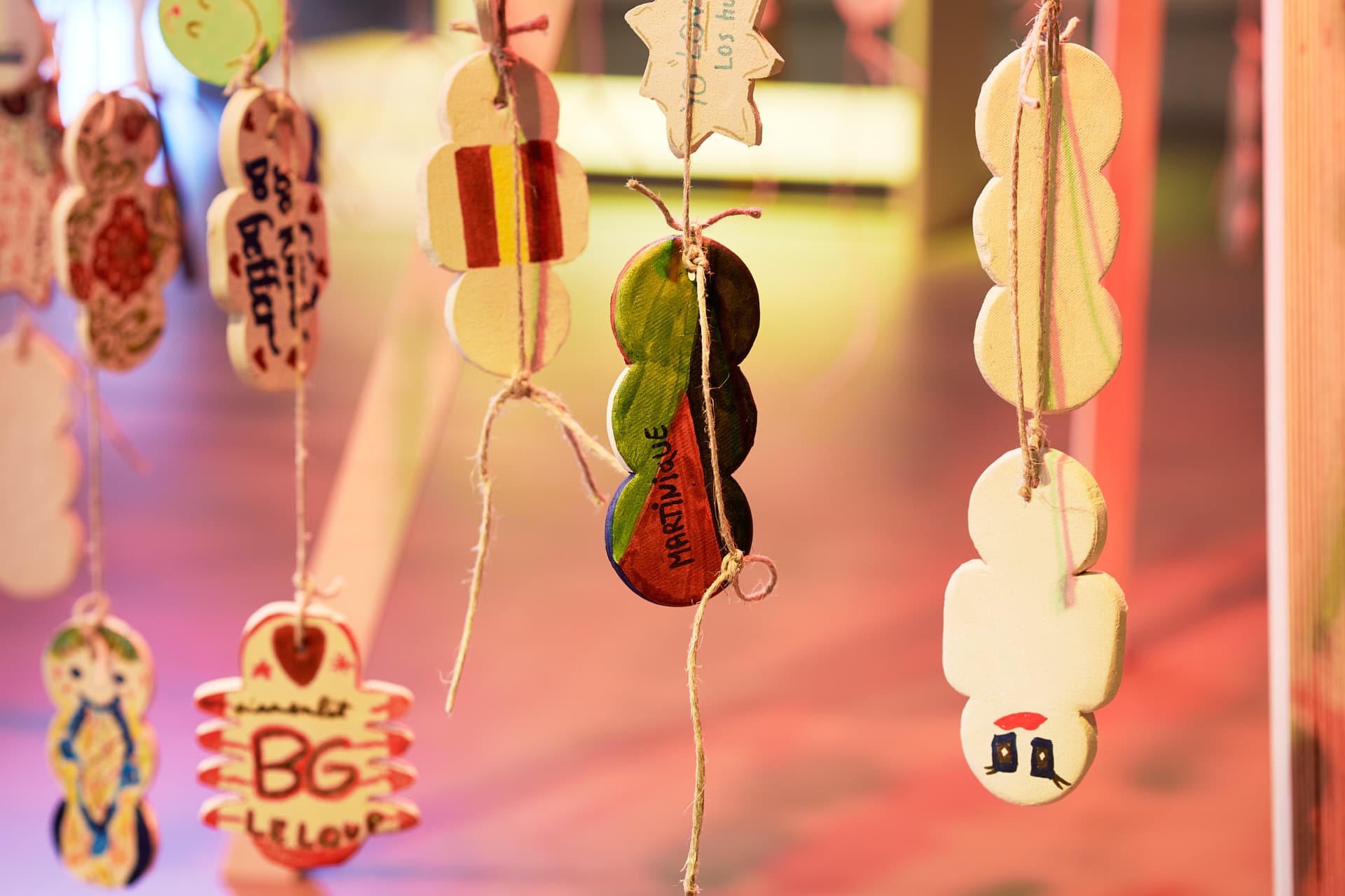 Objets décoratifs en céramique de forme circulaire suspendus, décorés de dessins et de textes dans une lumière chaude, détaché d'un premier plan flou.