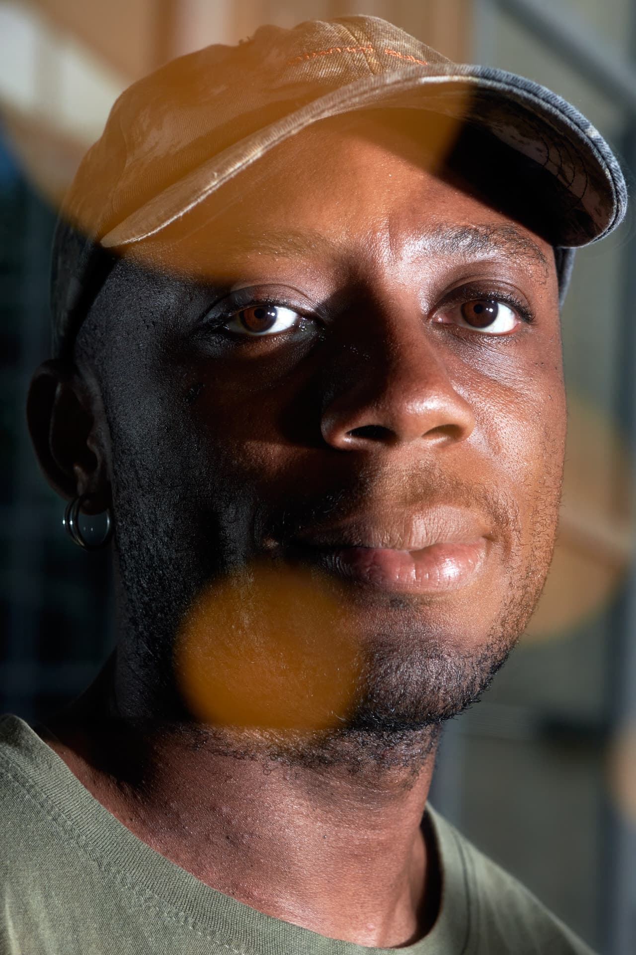 Portait d'un jeune homme de face portant une casquette avec une lumière lui éclairant le visage du côté droit.